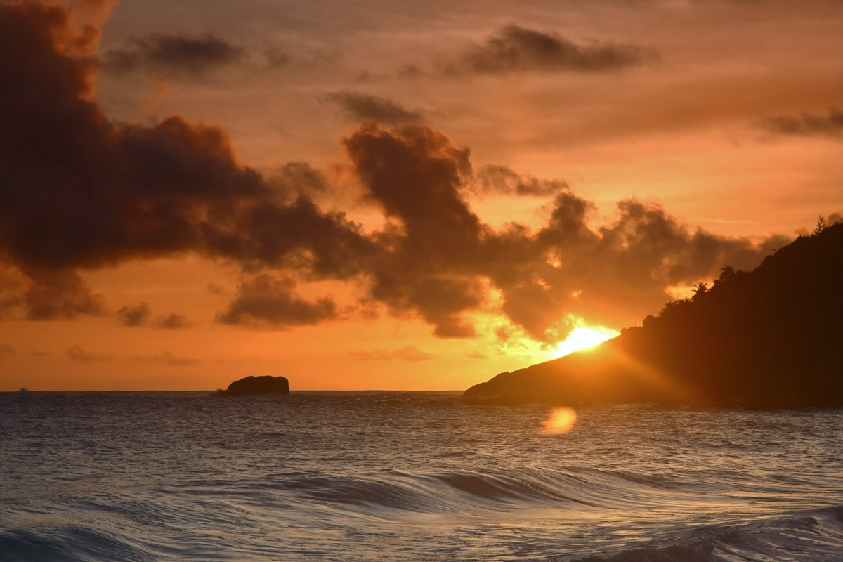 Een zonsondergang op een Seychelles zandbank met het water in de achtergrond.