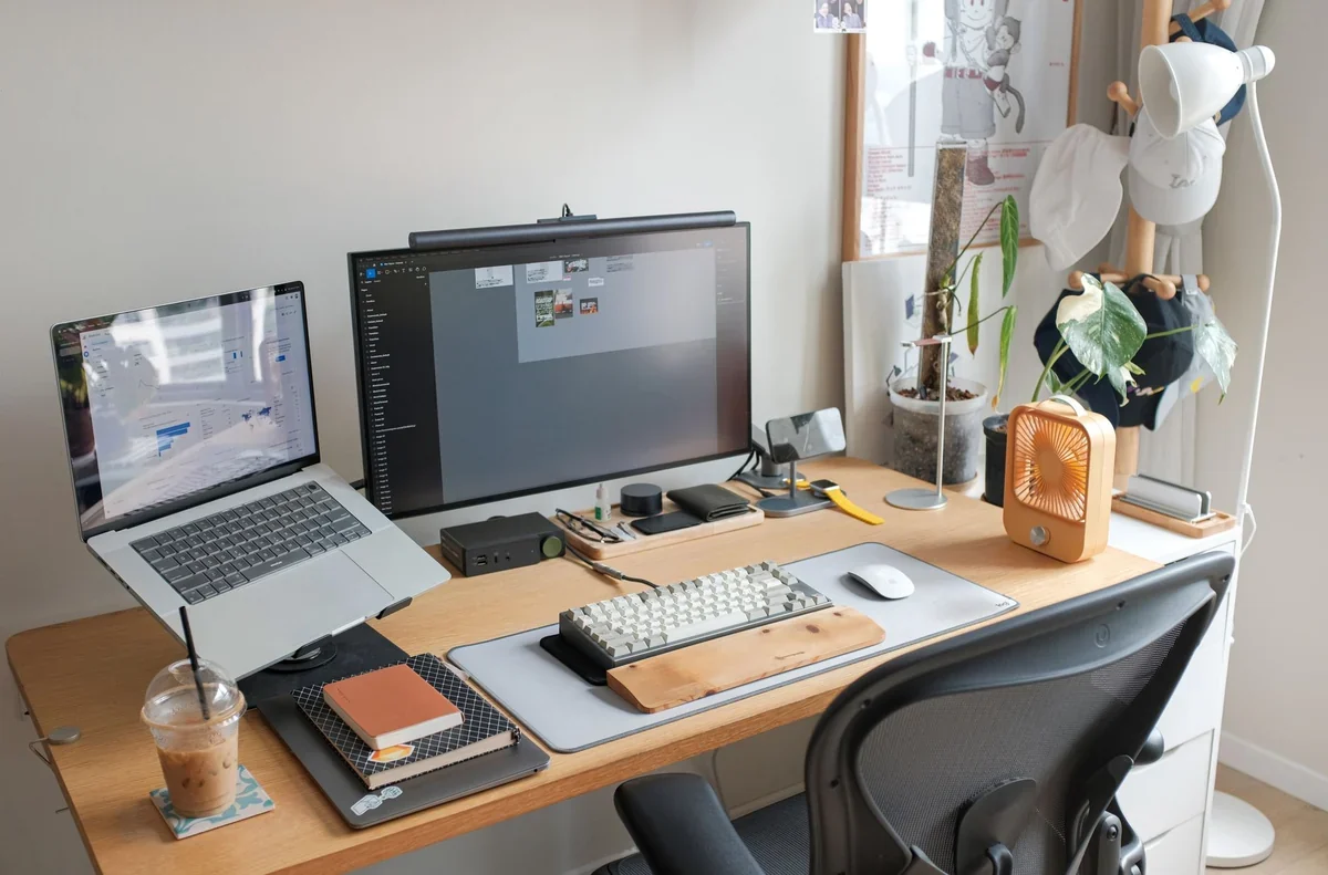 Uma mesa de escritório organizada com um laptop, uma xícara de café e um bloco de notas